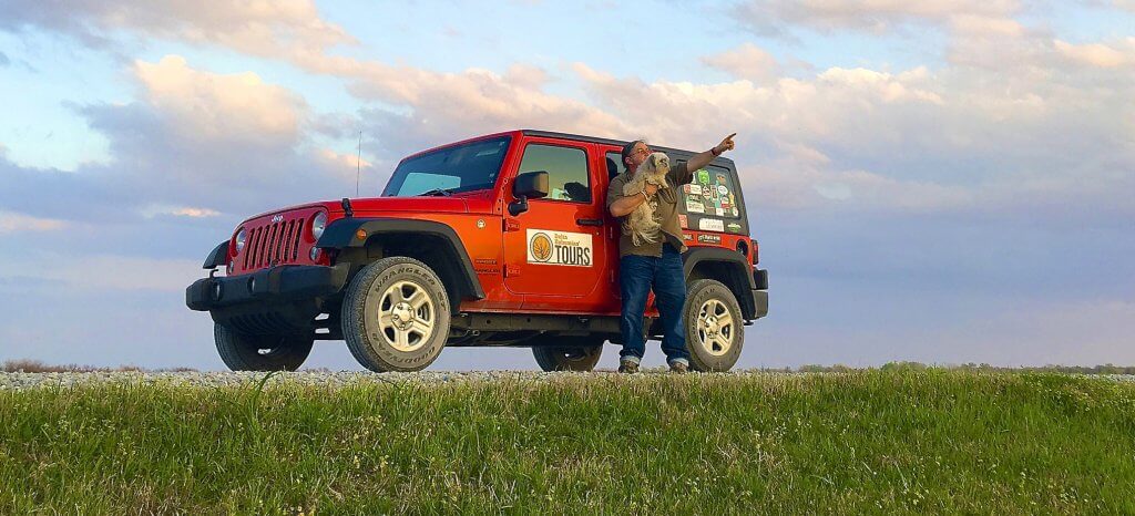 A man standing next to an orange jeep.