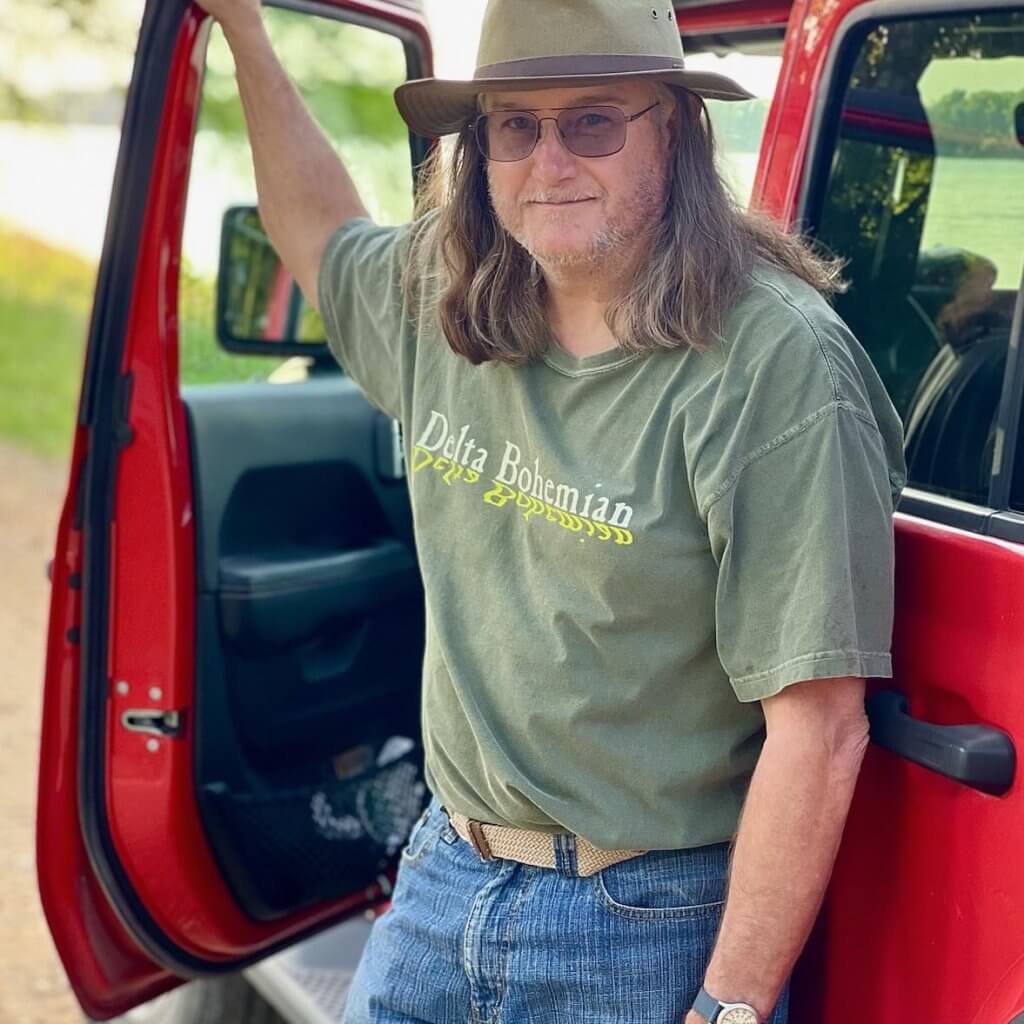 A man standing in the open door of his truck.